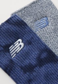 Két kötött New Balance zokni, az egyik sötétkék, a másik világosszürke, hímzett logókkal az azonos színekben és bordázott textúrával.