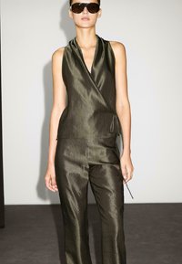 Olive green, silky wrap top with a deep v-neck and tie detail, paired with matching satin trousers featuring a subtle texture.