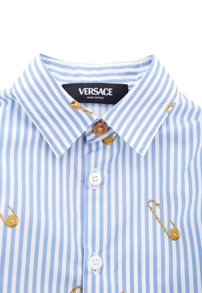 Niebieska i biała koszula w paski z zapięciem pod szyją, z haftem w kształcie złotego saksofonu i metką marki. Gładka tekstura materiału.