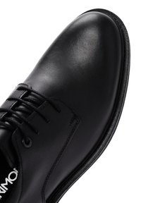 Chaussure habillée en cuir noir avec un bout arrondi, présentant une texture lisse, un design à lacets et une fine semelle en caoutchouc. Sans motifs ni accents.