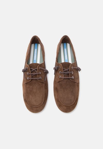 Paire de mocassins en daim marron à lacets, avec bouts arrondis et semelles intérieures rayées avec logo, vus de dessus sur fond blanc.