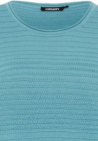Hellblauer, gestrickter Pullover mit rundem Ausschnitt. Die Textur zeigt abwechselnd horizontale Streifen in unterschiedlichen Dicken. Markentag sichtbar.