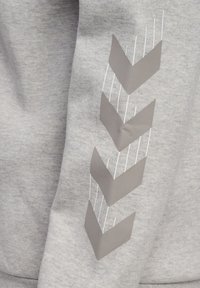 Tessuto grigio con quattro chevron grigi opachi rivolti verso il basso e sottili linee verticali bianche su uno sfondo grigio mélange.