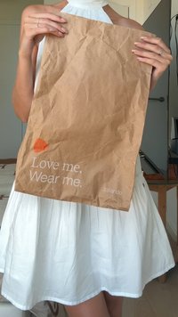 Brun papperspåse med rynkig textur, med vit text som säger "Älska mig. Bär mig." och en liten orange grafik. Varumärkeslogotyp: zalando.