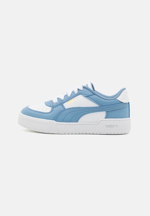 Lichtblauwe en witte sneaker met leren bovenkant, geperforeerde neus, veters en PUMA-logo. Heeft een witte rubberen zool en stikselaccenten.