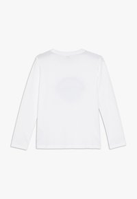 Camiseta blanca de manga larga hecha de algodón, con cuello redondo y espalda lisa. Presenta una textura suave y un dobladillo recto. Sin gráficos visibles.