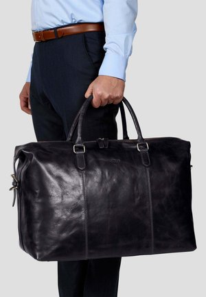 Black leather duffel bag with dual handles, top zipper closure, and embossed logo detail. Smooth texture with slight sheen.