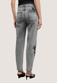 Šedé riflové kalhoty s vysokým pasem a rovným střihem, s jemným černým květinovým vzorem podél strany a dvěma zadními kapsami.