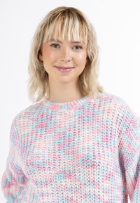 Kötött pulóver pasztell rózsaszín, kék és fehér árnyalataiban; kerek nyakkal és laza illeszkedéssel rendelkezik, az egész felületét struktúrált minta díszíti.