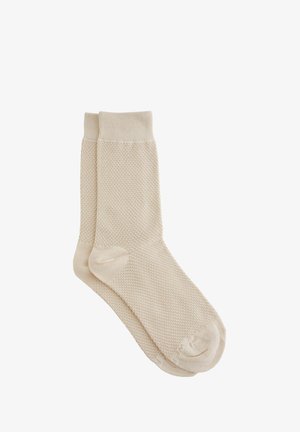 Beige pamut zoknik texturált kötött mintával, bordás szegéllyel és sima lábujjvarrással. Közép-vádli hosszúságúak.