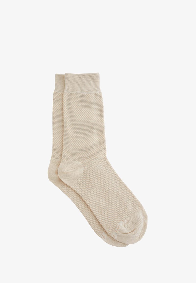 Beige pamut zoknik texturált kötött mintával, bordás szegéllyel és sima lábujjvarrással. Közép-vádli hosszúságúak.