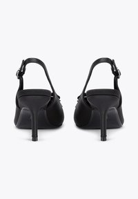 Sandales à talons hauts noires avec une finition en cuir lisse, dos ouvert et bride de cheville avec une boucle en argent. Design notable avec un talon pointu.