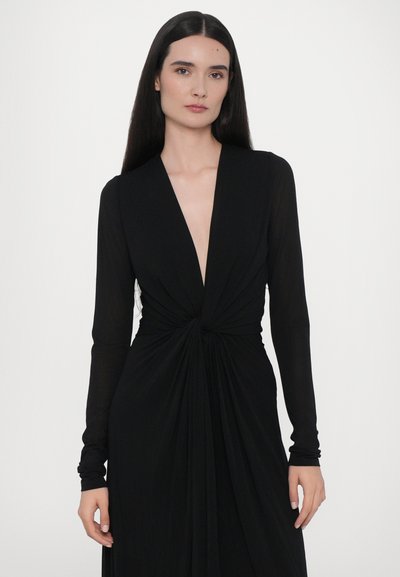 Vestido negro de manga larga con un escote en V profundo, detalle de twisted en la cintura y falda fluida. Fabricado en una tela suave y ligera.