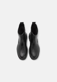 Botas de tobillo de cuero negro con paneles laterales elásticos, punteras redondeadas y suela de goma texturizada. Acabado liso sin herrajes o adornos visibles.