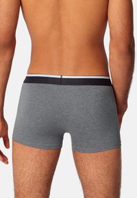 Boxer in cotone grigio con elastico nero e una striscia bianca a contrasto. I pantaloni hanno una vestibilità aderente e una texture liscia.