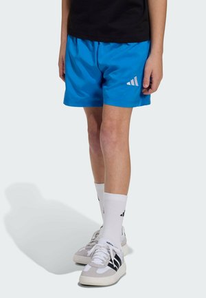 Modré sportovní šortky z lehké tkaniny, s elastickým pasem a bílým logem Adidas. Doplněné bílými ponožkami a teniskami.