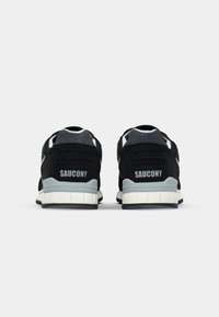 Black suede and mesh sneakers with a grey accent and white midsole. "SAUCONY" logo on the heel, featuring textured detailing.