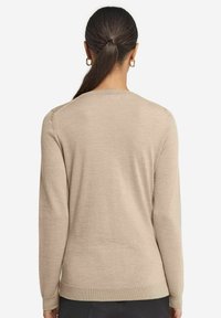Beige långärmad tröja med rund halsringning, ribbade ärmslut och nederkant. Tillverkad av ett mjukt material med en slät yta och minimalistisk design.