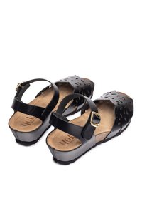 Black sandals with perforated design, adjustable strap with gold buckle, cork insole, and textured outsole for grip.