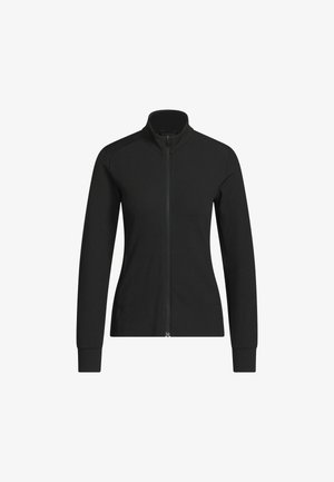 Musta naisten istuva vetoketjullinen takki pystykauluksella, pitkät hihat ja resorikuosi valkoisella taustalla.