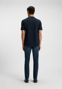 Navy short-sleeved t-shirt with a round neck, paired with dark blue denim jeans. The fabric appears smooth with a slight texture.