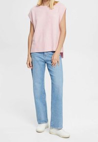 Haut sans manches en maille rose clair avec un ourlet côtelé, associé à un jean droit bleu clair et des baskets blanches.