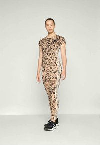 Leopárdmintás sportos szett bézs árnyalatokban, melyhez egyfekete testhez simuló felső és oldalsó csíkos leggings tartozik, sima, rugalmas anyagból készült.