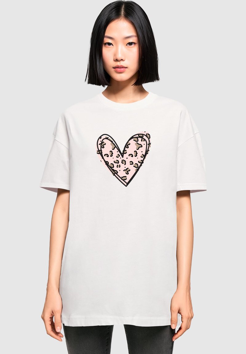 Witte oversized T-shirt met een roze hartgrafiek met een luipaard-prints patroon in het midden. Korte mouwen, ronde hals.