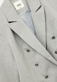 Grijs gestreepte dubbelgeknoopte blazer met scherpe revers, zilveren knopen en een gladde lichtblauwe voering. Maat 38 label zichtbaar.