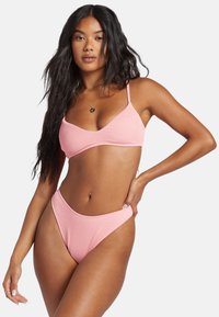 Ružový rebrovaný bikiny set s braletovým vrchom a nastaviteľnými ramienkami, doplnený vysokými nohavičkami, ktoré vystavujú textúrovanú látku.