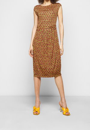 Knælængde kjole med kappelærmer i gult med rødt og grønt geometrisk mønster. Båret med gule åbne peep-toe hæle med sløjfedetalje.