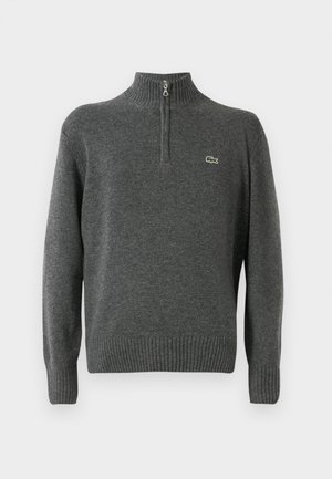 Suéter gris de punto con medio cierre, puños y dobladillo acanalados, hecho de tejido suave. Presenta un pequeño logo verde de Lacoste en el pecho.
