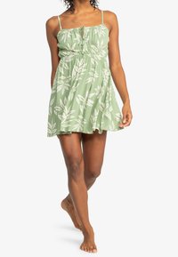 Vaaleanvihreä mekko, jossa on vetturoidut vartalo ja ohuet hihnat. Koristeena valkoiset lehvämallit koko mekossa. Polvipituinen, rento istuvuus.