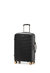 Maleta negra de carcasa dura con líneas horizontales texturizadas, asa telescópica, agarre lateral y cuatro ruedas dobles giratorias con detalles dorados.