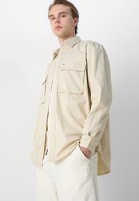 Lichtbeige button-up overhemd van katoen, met twee borstzakken, een relaxed fit en lange mouwen met knoopmanchetten.