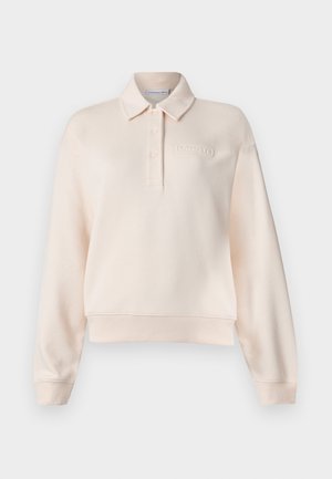 Svijetlopinkani polo dukserica s kragnom, tri gumba na prednjem dijelu i utisnutim logotipom brenda na prsima. Mekani materijal, ležeran kroj.