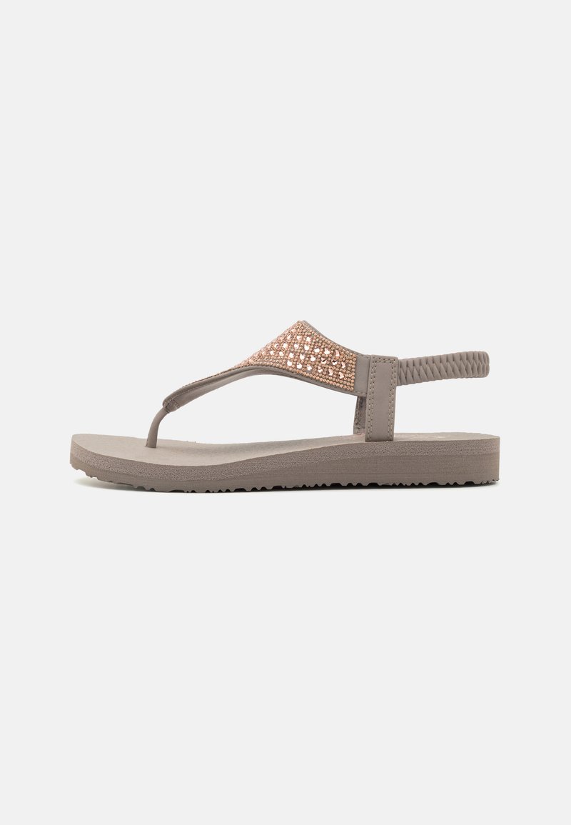 Ruske flip-flop sandale s teksturiranim remenom koje imaju akcentiranje u rozoj zlatnoj boji, ravnim gumeni đonom i dizajnom između prstiju. Fleksibilna, lagana konstrukcija.