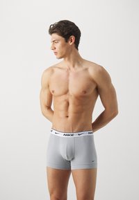 Los bóxer grises de Nike cuentan con una cinturilla elástica negra con el logo de la marca. La tela parece suave con un diseño ajustado y sin patrones visibles.