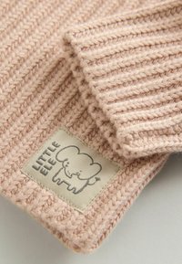 Detail eines gestrickten rosa Wollpullovers mit geripptem Textur und einem cremefarbenen Patch mit einem Elefantenlogo und dem Text "LITTLE ELF".