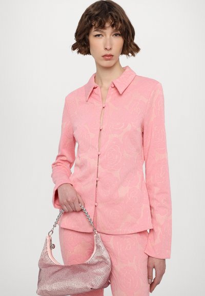 Pink textured blazer with floral pattern, button closure, and a collar, paired with a shiny pink handbag featuring a chain handle.
