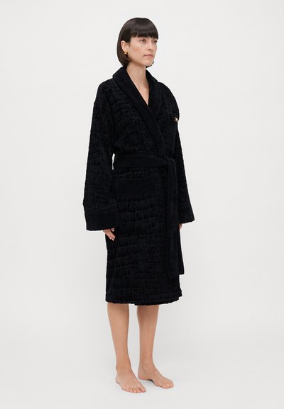 Μαύρο μπουρνούζι από υφασμάτινη υφή με σχέδιο κροκοδείλου, με γιακά σε σχήμα σαλονιού, ζώνη και πλαϊνές τσέπες.