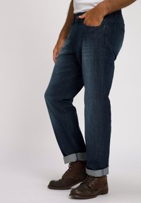 Jeans de denim azul oscuro con diseño de pierna recta, que cuentan con un dobladillo tipo puño, cinco bolsillos y un cierre con botón de metal.