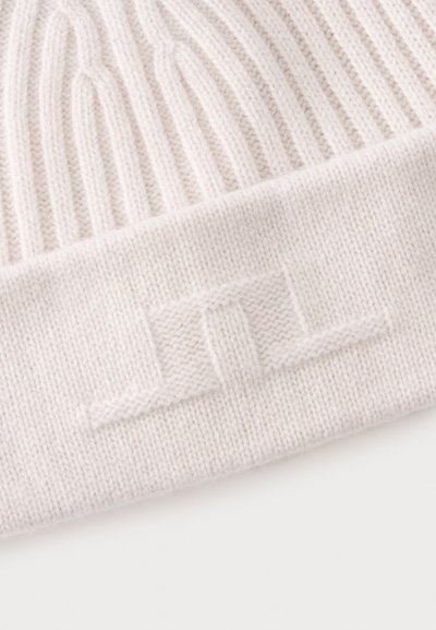 Gros plan d'un tissu tricoté côtelé beige clair avec une bande épaisse et un motif rectangulaire en relief.