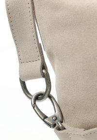 Cinghia per borsa in suede beige con un gancio in metallo argentato. Texture liscia, cinghia rettangolare e dettagli di cucitura visibili sul bordo.