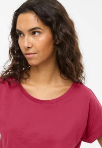 Κοντομάνικη μπλούζα με στρογγυλή λαιμόκοψη σε βαθύ ροζ χρώμα, κατασκευασμένη από μαλακό βαμβάκι, με άνετη εφαρμογή και λεία υφή.