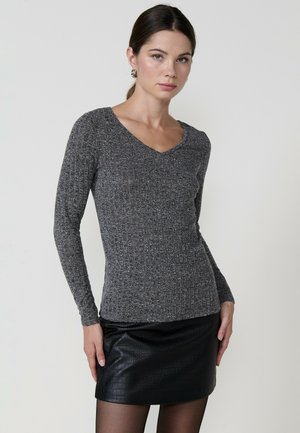 Top gris de manga larga con escote en V y un patrón de punto texturizado. Combinado con una minifalda negra de cuero sintético, que presenta un diseño ajustado y elegante.