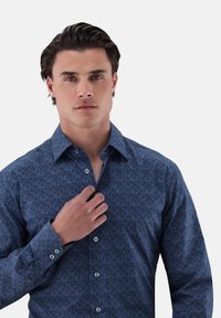 Dark blue shirt with a geometric pattern, long sleeves, button-down collar, and silver buttons, featuring a textured fabric.