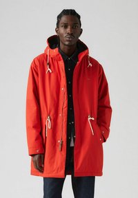 Punainen vedenpitävä parka säädettävällä hupulla, nyöreillä, vetskarilla edessä, sivutaskuilla ja rento fit. Oma smooth texture ja metalliset yksityiskohdat.