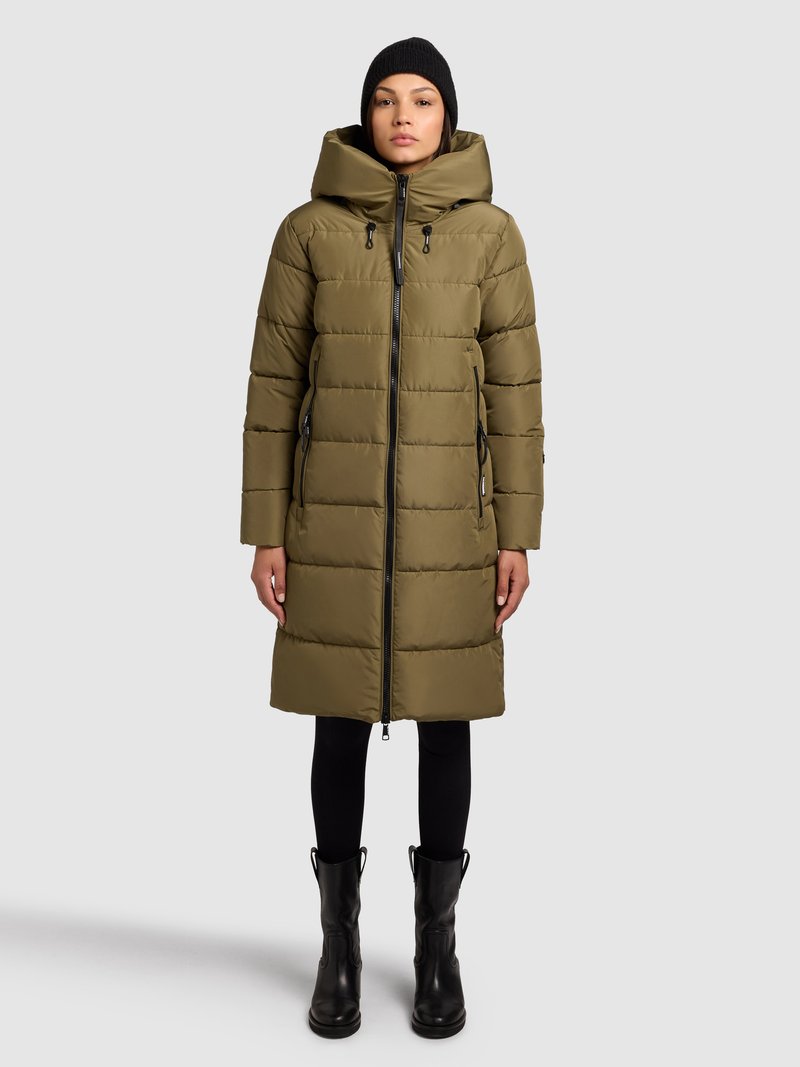 Oliiviroheline sule mantel kapuutsiga, vertikaalse õmblusmustriga, ees lukuga ja küljetaskutega, kombineeritud mustade retuuside ja pahkluu saabastega.