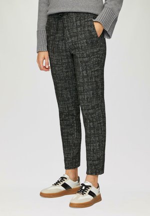 Zwarte geruite broek van een textuurstof, met zijzakken en een elastische tailleband, gecombineerd met zwart-wit lage sneakers.
